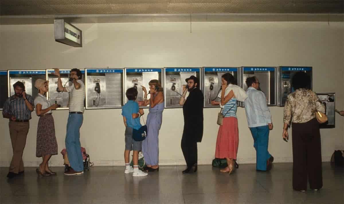 People in the 1970s using public pay phones in an airport